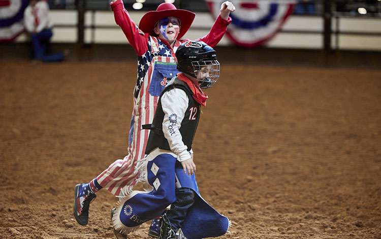 A young rodeo clown cheering on a kid competitor in Mutton Bustin